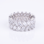 A silver-toned eternity band ring set with multiple rows of clear baguette-cut gemstones, photographed on a clean white background with a soft reflection below.